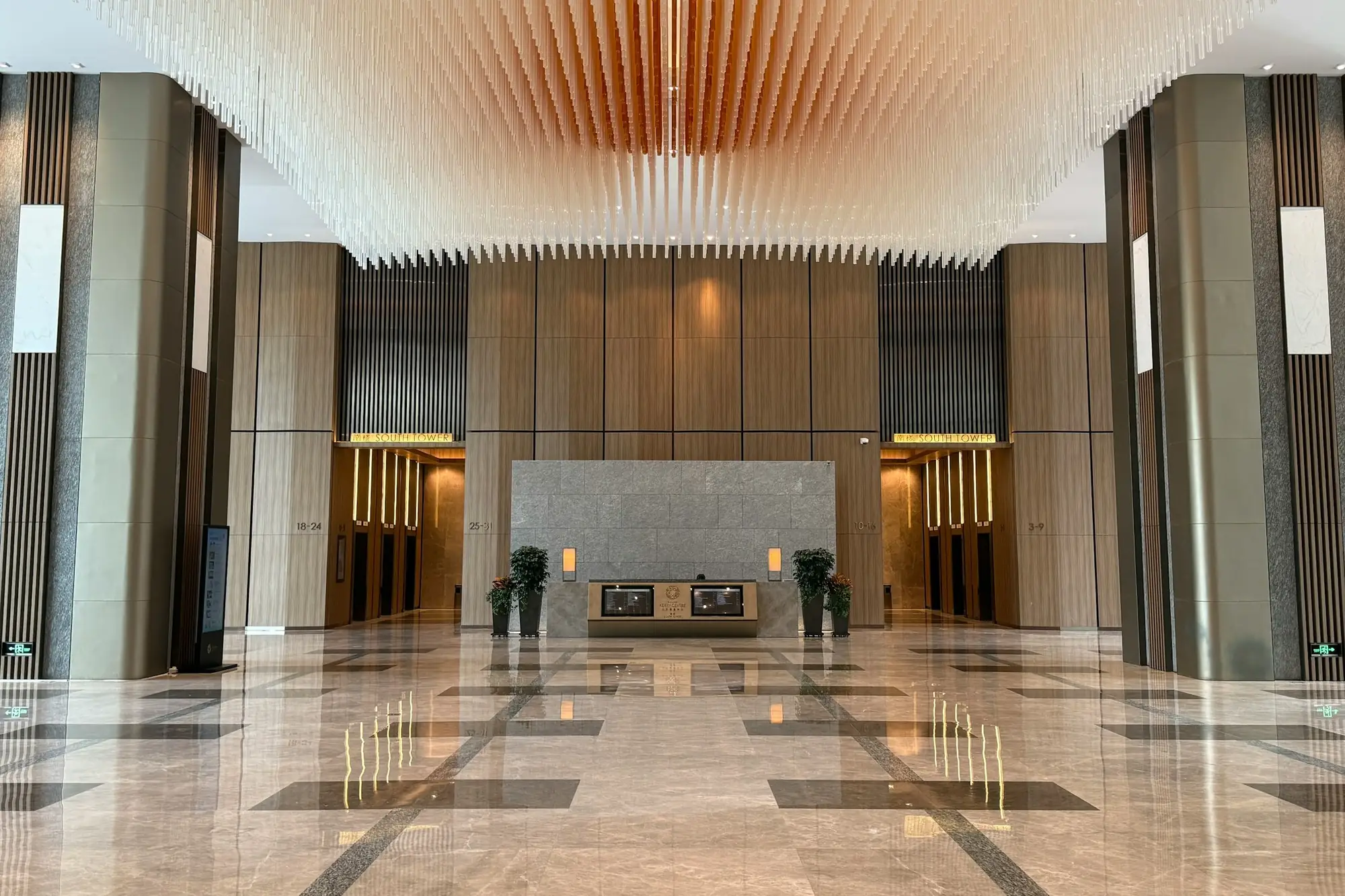 A hotel lobby with a wooden wall above the reception desk and white stone panels on the pillars