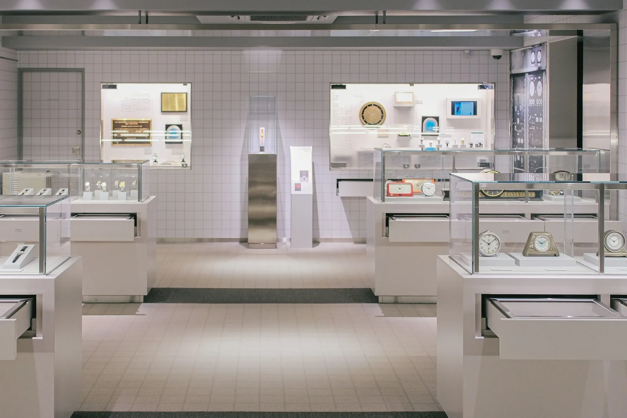 A watch shop with two lit display niches in the back wall and a printed poster on a stand